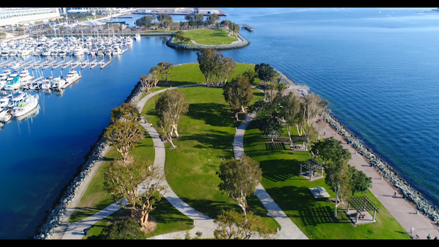 Aerial view of a park, boats and the ocean in Downtown San Diego, with people walking.