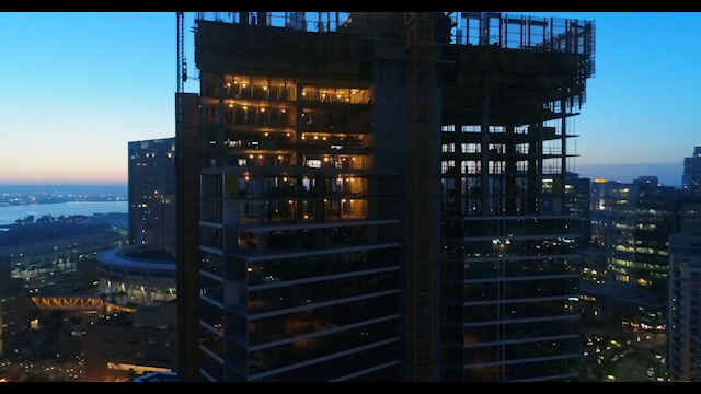Aerial view of the downtown streets, the skyline and the buildings in Downtown San Diego, with a work crew on site.