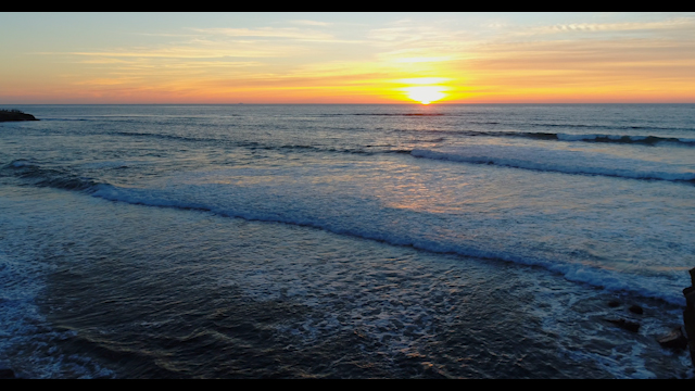 Low aerial view of the cliffs, the surf and the ocean at Sunset Cliffs.