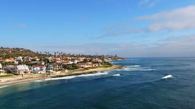 Aerial view of the cliffs, the surf and palm trees at Windansea.