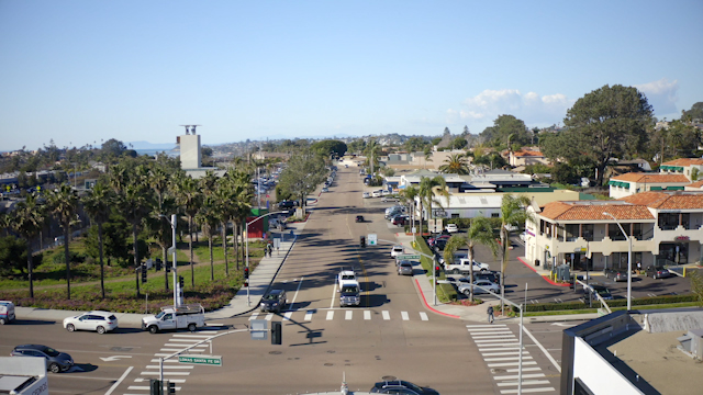 Low aerial view of the downtown streets, palm trees and homes in Solana Beach, with people walking.