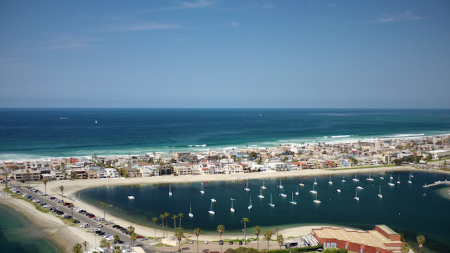 Tracking shot of the  marina at Mission Bay with ocean views | Drone Video