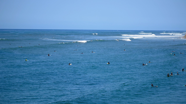 Low aerial view of the beach, the surf and the ocean in Pacific Beach, with surfers out.