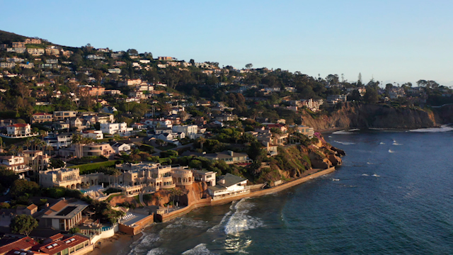Low aerial view of the cliffs, the surf and the ocean at La Jolla Shores.