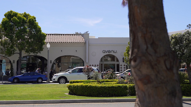 The downtown streets, the buildings and traffic in Coronado, with people walking.