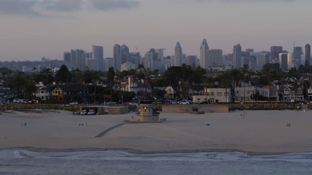 Low aerial view of the beach, the surf and the skyline at Coronado Beach.
