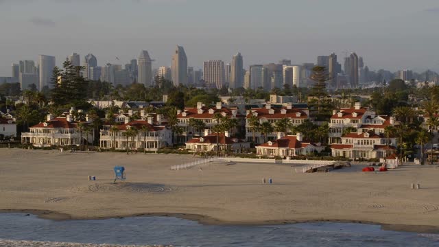 Low aerial view of the beach, the skyline and palm trees at Coronado Beach.