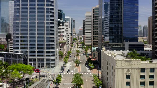 Low aerial view of the downtown streets, the skyline and palm trees at Gaslamp, with people walking.