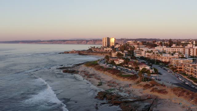 Aerial view of the beach, the surf and palm trees at La Jolla Cove, with people walking.