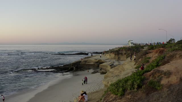 The cliffs, the ocean and the beach at La Jolla Cove, with people walking.