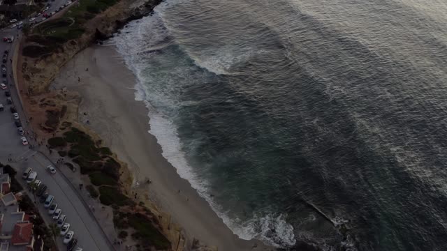 Aerial view of the beach, the surf and the ocean at La Jolla Cove, with people walking.