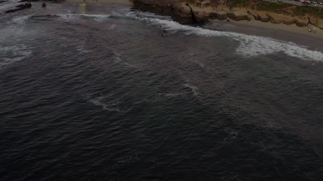 Aerial view of the cliffs, the surf and the ocean at La Jolla Cove.