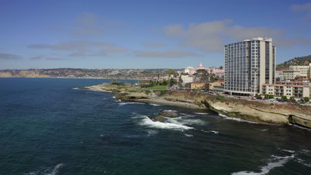 Low aerial view of the cliffs, the ocean and homes at La Jolla Cove.
