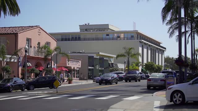 The downtown streets, palm trees and homes at La Jolla Cove, with people walking.