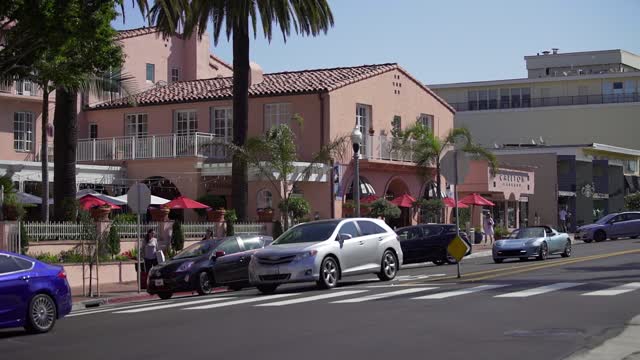 The downtown streets, palm trees and the buildings at La Jolla Cove, with people walking.
