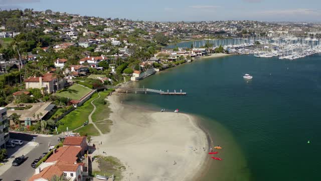 Aerial view of the harbor, boats and palm trees in Point Loma, with paddlers on the water.
