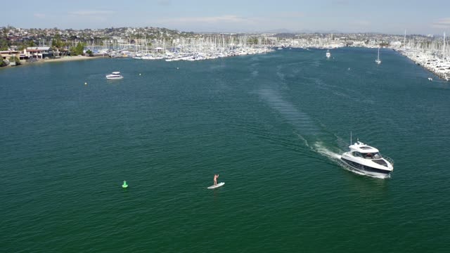 Low aerial view of the harbor, boats and the bay in Point Loma, with paddlers on the water.