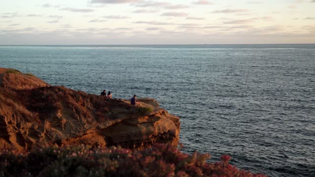 Elevated view of the cliffs, the ocean and open country at Sunset Cliffs, with people walking.