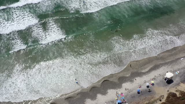 Aerial view of the beach, the surf and the ocean at Leucadia, with swimmers in the water.