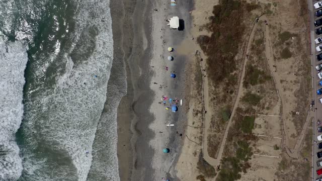 Aerial view of the beach, the surf and the ocean at Leucadia, with a crowd gathered.