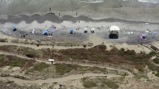 Aerial view of the beach, the surf and the ocean at Leucadia, with a crowd gathered.