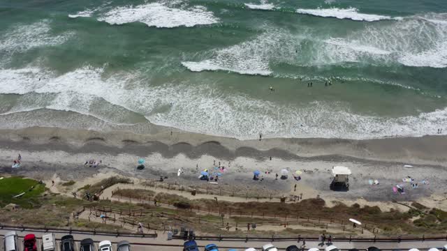 Aerial view of the beach, the surf and the ocean at Leucadia, with swimmers in the water.