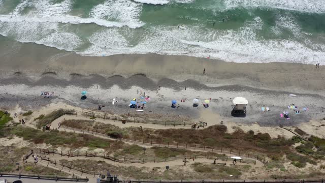 Aerial view of the beach, the surf and the ocean at Leucadia, with people walking.