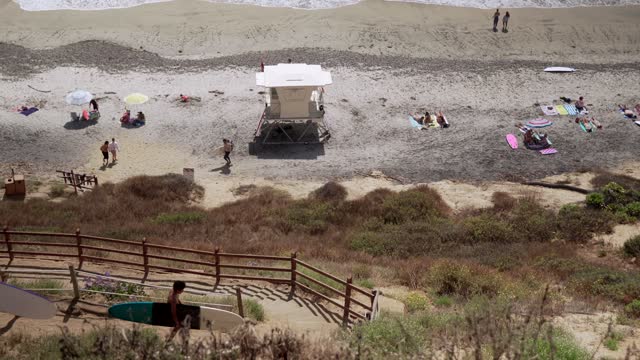 Elevated view of the beach, the surf and the ocean at Leucadia, with people walking.