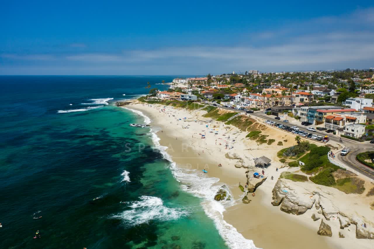 Aerial view of the beach, the surf and the ocean at Windansea, with people walking.
