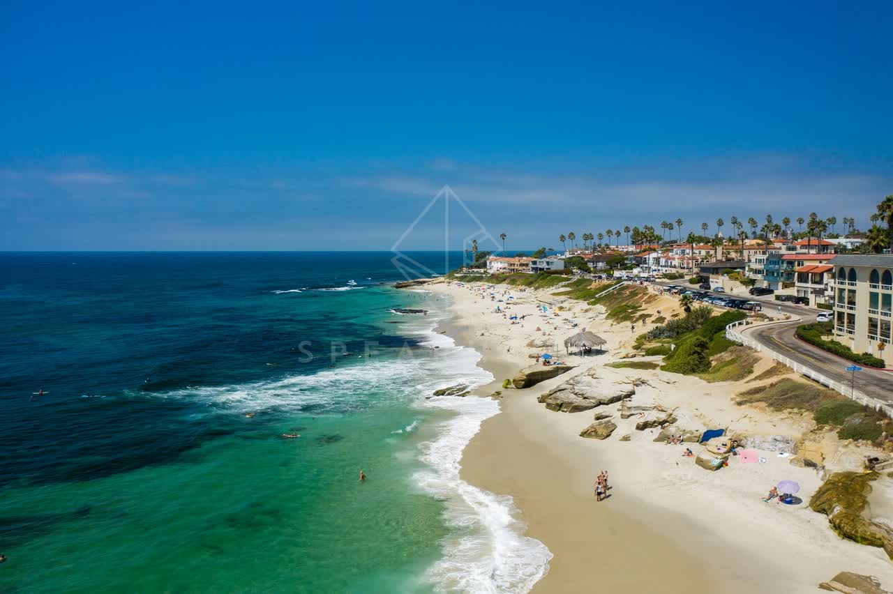 Aerial view of the beach, the surf and palm trees at Windansea, with people walking.