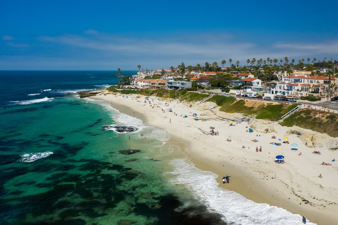Aerial view of the beach, the surf and palm trees at Windansea, with people walking.