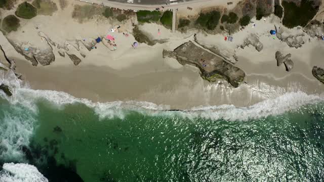 Aerial view of the beach, the surf and the ocean at Windansea, with people walking.