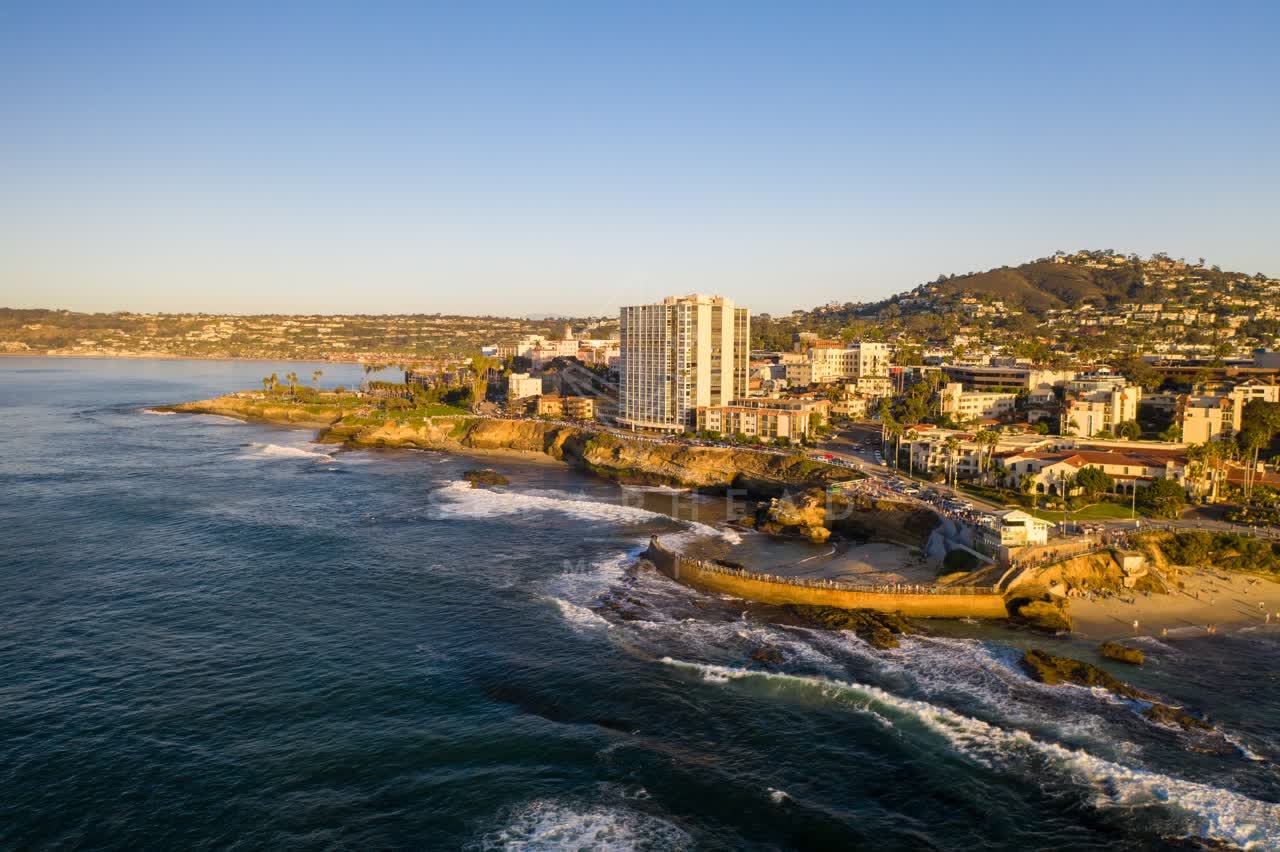 Aerial view of the cliffs, the surf and palm trees at La Jolla Cove.