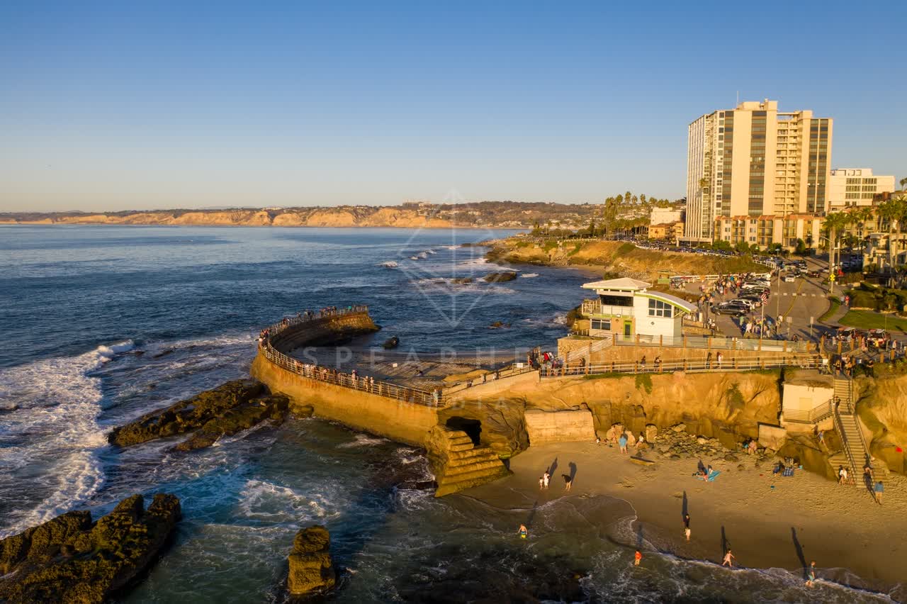 Aerial view of the cliffs, boats and the ocean at La Jolla Cove, with a crowd gathered.