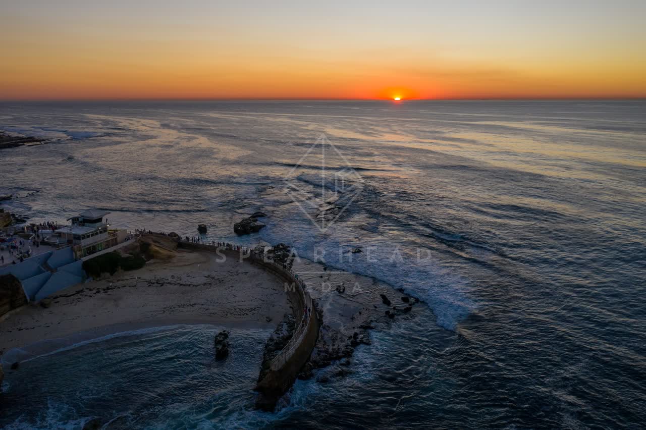 Aerial view of the beach, the surf and the ocean at La Jolla Cove, with a crowd gathered.