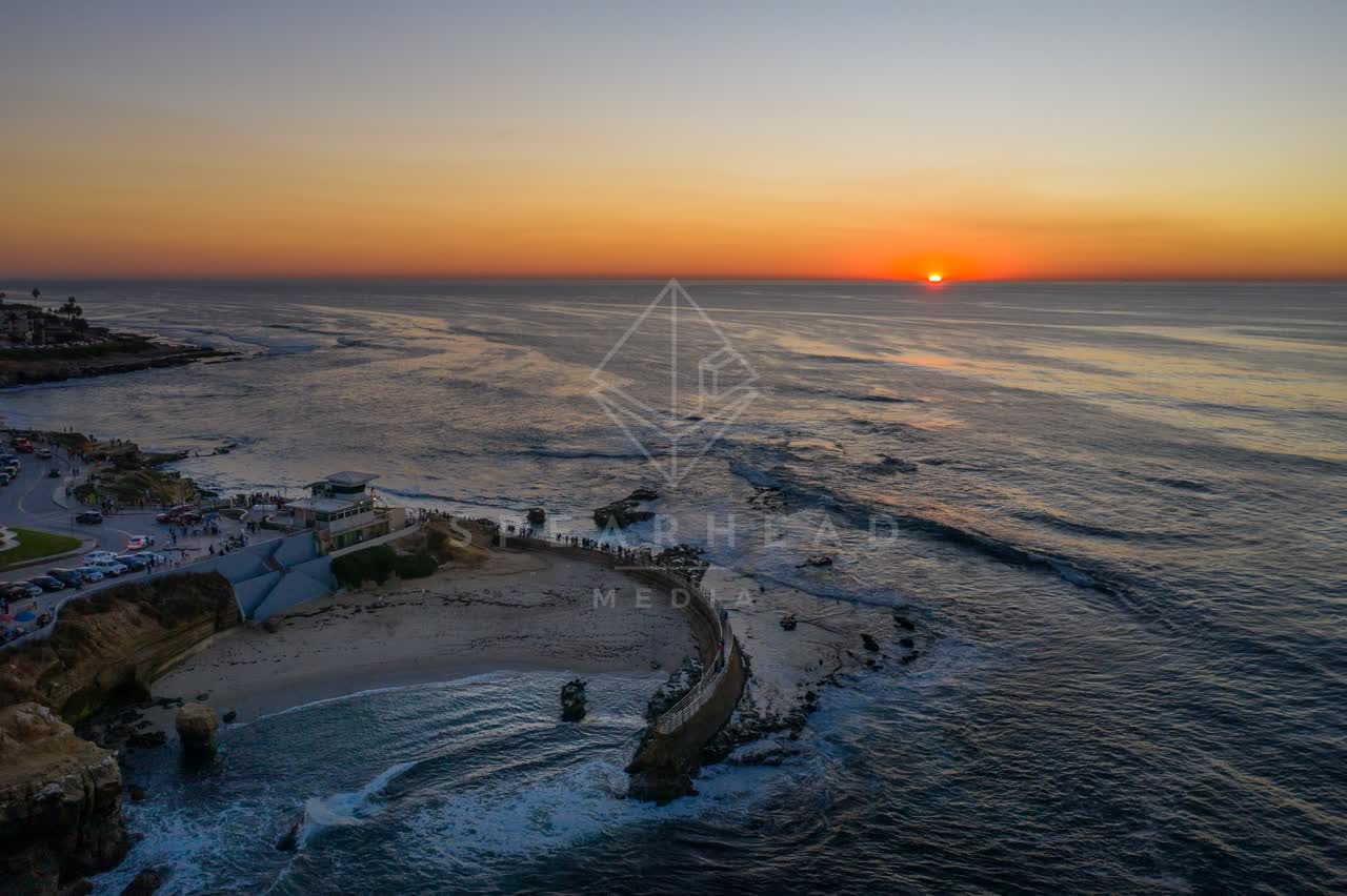 Aerial view of the cliffs, the ocean and the beach at La Jolla Cove, with a crowd gathered.