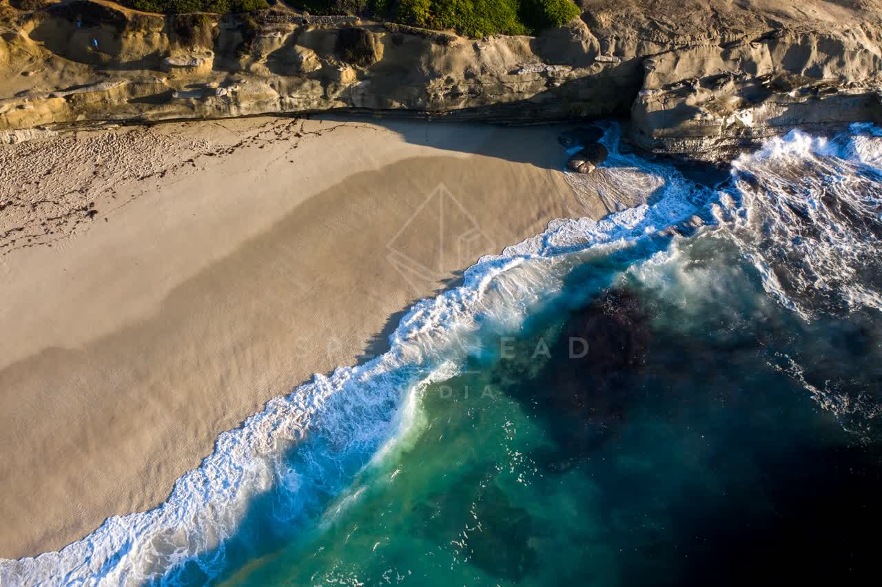 Aerial view of the cliffs, the surf and the ocean at La Jolla Cove.
