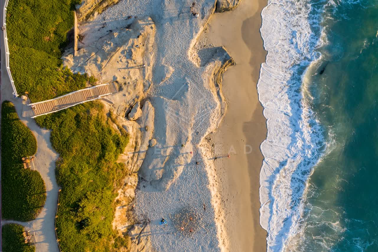 Aerial view of the beach, the surf and the ocean at Windansea, with people walking.