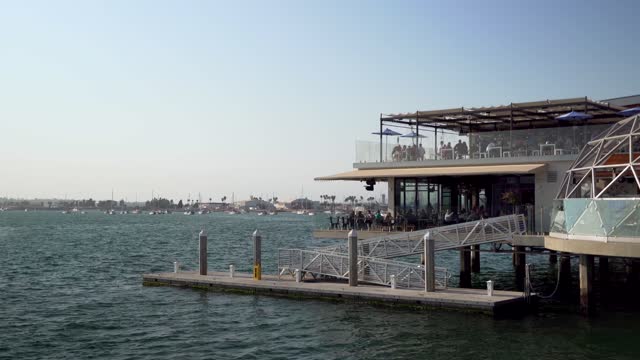 The harbor, boats and palm trees at Waterfront, with people eating outside.