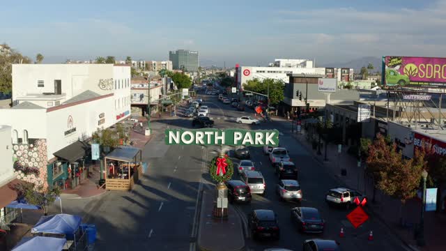 Low aerial view of the downtown streets, palm trees and the buildings in North Park, with people walking.