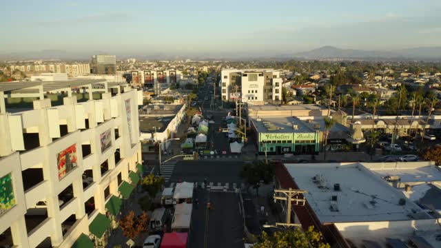 Low aerial view of the downtown streets, palm trees and homes in North Park, with a crowd gathered.