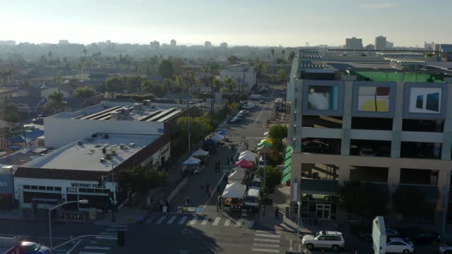 Low aerial view of the downtown streets, palm trees and homes in North Park, with a crowd gathered.