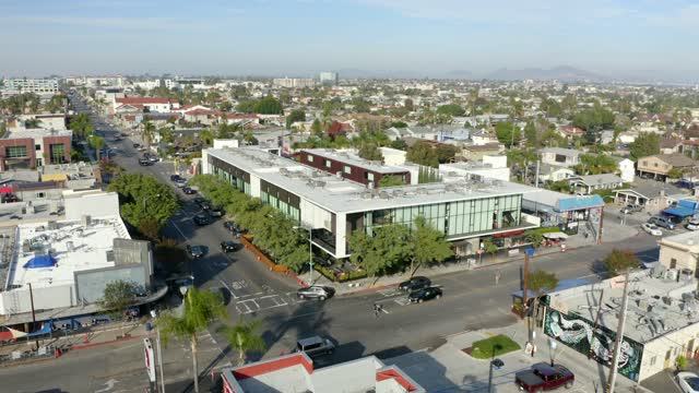 Low aerial view of a residential street, homes and the buildings in North Park, with people walking.