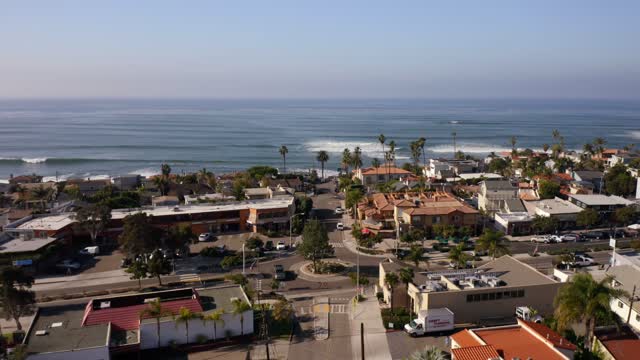 Low aerial view of a residential street, the surf and palm trees at Bird Rock.