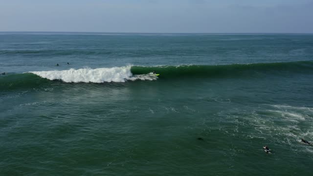 Low aerial view of the beach, the surf and the ocean at Bird Rock, with surfers out.