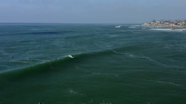 Low aerial view of the beach, the surf and the ocean at Bird Rock, with surfers out.