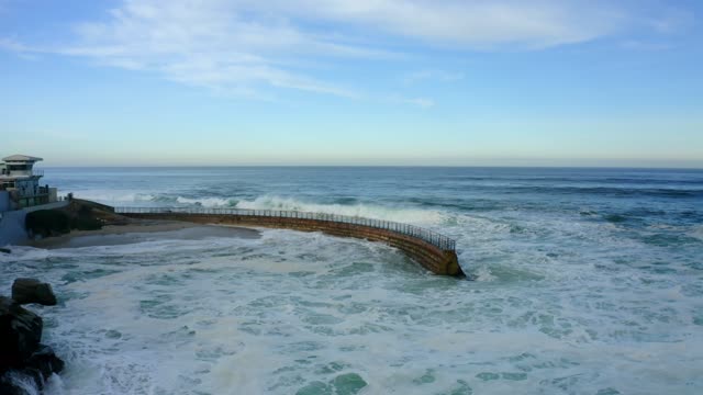 Low aerial view of the cliffs, the surf and the ocean at La Jolla Cove.