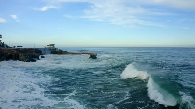 Low aerial view of the cliffs, the surf and the ocean at La Jolla Cove.