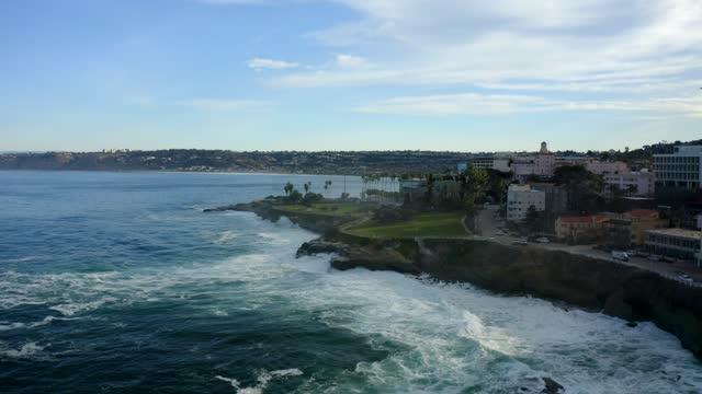 Aerial view of the cliffs, the surf and palm trees at La Jolla Cove.