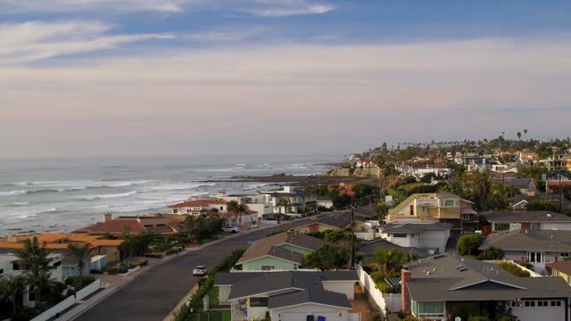 Low aerial view of a residential street, the surf and palm trees at Bird Rock.